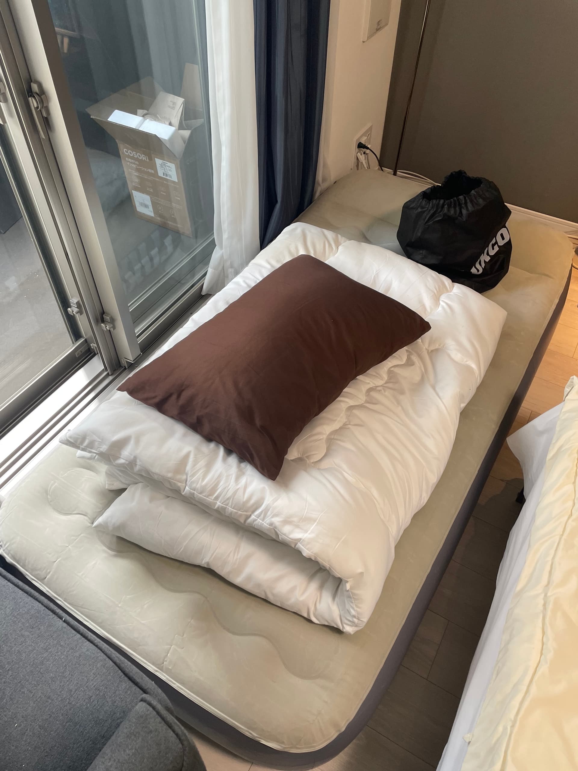 Angled front view of air mattress with comforter, pillow, and bag.